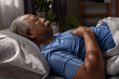 © Ratirat - Senior man sleeping peacefully in bed at night in cozy bedroom, hands on chest. Concept of healthy sleep, rest, aging lifestyle, bedtime routine, relaxation and senior health care at home.