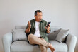 © ArvStd - A man sitting on a sofa at home while talking on a cellphone, angry gestures and annoyed expressions, aggressive, stressed, arguing over the phone, showing negative emotions while raising his hands.