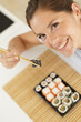 © auremar - woman holding sushi roll between chopsticks