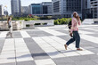 © wavebreak3 - Diverse women crossing tiled rooftop, woman in pink hoodie holding smartphone, backpack, copy space