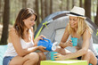 © auremar - sisters sitting near tent on camping trip drinking with mugs