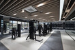 © Namsun - Empty modern fitness gym interior with cardio machines and strength training equipment.