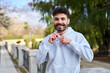 © Oscar - Young man smiling adjusting hoodie outdoors