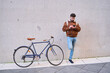 © Oscar - Courier man checking smartphone by bicycle in urban setting