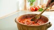 © Ksenia Pestereva - Hand stirring homemade tomato sauce with a wooden spoon in a clay pot. Cooking healthy Italian food in kitchen