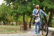© Pixel-Shot - Young happy man with helmet and bicycle walking in park