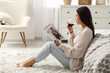 © Pixel-Shot - Young Asian woman drinking wine and reading magazine on floor in bedroom