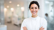 © Kowit - A confident young woman in a white lab coat smiles warmly with her arms crossed in a bright, modern professional setting.