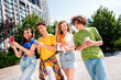 © deagreez - Group of cheerful teens exploring their phones outdoors during bright sunny day in a modern city environment