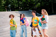© deagreez - Group of Teenagers Socializing Outdoors in Urban Setting During Summer Day, Holding Study Supplies and Backpacks