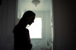 © kieferpix - silhouette of tired woman leaning against wall in bathroom, stress and mental health concept
