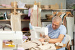 © JackF - Mature man dressmaker sewing fabric on sewing machine in sewing workshop