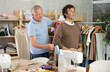 © JackF - Elderly man tailor taking body measurements of adult man with measuring tape in sewing workshop