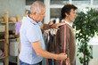 © JackF - Older tailor with a with measuring tape takes measurements for a male client. Production of clothes according to individual measurements in a sewing workshop