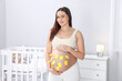 © New Africa - Pregnant woman with notes with different names on her belly indoors