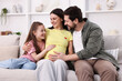 © New Africa - Pregnant woman, her husband and daughter on sofa at home