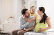© New Africa - Pregnant woman, her husband and daughter at home. Space for text