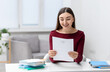 © New Africa - Happy woman with acceptance letter from university at table indoors