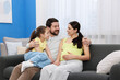 © New Africa - Pregnant woman, her husband and daughter on sofa at home