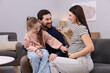 © New Africa - Pregnant woman, her husband and daughter on sofa at home