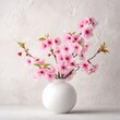 © Rakhman - Still life of pink cherry blossoms arranged in a minimalist white vase against a textured backdrop creating a serene, springtime, floral arrangement.