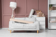 © Pixel-Shot - Grey sofa, standard lamp and chest of drawers wrapped in stretch film near brown wall
