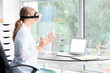 © Pixel-Shot - Female doctor using VR glasses with controllers at table in clinic