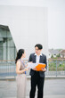 © laddawan - Asian business professionals reviewing documents and reports outdoors, discussing strategy, planning and corporate management