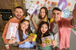 © Pixel-Shot - Group of young friends with gifts taking selfie at Birthday party in kitchen