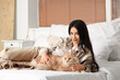 © Pixel-Shot - Pretty young woman with cute Maine Coon cat lying on bed at home