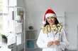 © Pixel-Shot - Young female doctor with Santa hat and balloons in shape of figure 2026 in clinic