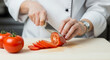 © Erlangga - Chef Slicing Tomato on Cutting Board Preparing Ingredients for Cooking in Kitchen