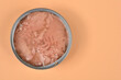 © nahhan - Top view of an open round metal can filled with tuna chunks in brine placed on an pale orange paper surface with copy space on the right