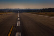 © Mint Images - View down an airport runway, an aircraft preparing for take off.
