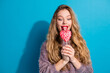 © deagreez - Young woman with heart shaped lollipop smiles against blue background for fashion lifestyle promotion