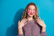 © deagreez - Playful young woman with pink stickers on cheeks wearing a purple sweater against a bright blue background