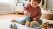 © Andres Mejia - Focused toddler girl plays with pastel wooden blocks and toys.