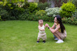 © leungchopan - Baby playing happily with mother on grass
