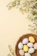 © SuperGlück - Colorful eggs in a woven basket on a yellow background with flowers for spring decorations