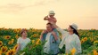 © Victoriia - Happy children dad mom farmer, play in sunflower field. Parents children in nature. Family travel. Happy family, young son on shoulders of his farmer father mother daughter walking in sunflower field.