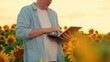 © Victoriia - Farmer businessman inspecting sunflower in field. Modern farmer growing sunflower plantations. Farmer man working in sunflower field with computer tablet. Digital technologies in agriculture. Business