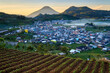 © Travel 'n' Lifestyle - View of a town nestled in a valley with its colorful houses and lush green fields contrasting against the majestic mountain backdrop, Banjarnegara, Indonesia.