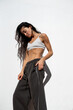 © sutulastock - Athletic adult woman standing against white wall in sunlight, wearing sports bra and loose pants, looking down with relaxed posture, highlighting defined abdominal muscles