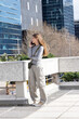 © wavebreak3 - Female standing on urban overpass holding smartphone to ear wearing grey top olive crossbody bag