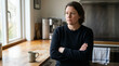 © Vera - Woman with arms crossed looking thoughtfully in modern kitchen