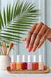 © Ulubek - Woman's hand showing coral manicure above row of colorful nail polish bottles on table