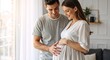 © Vasiliy - Young pregnant couple holding belly near window at home. Happy husband and wife expecting baby. Maternity and family concept