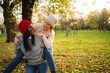 © Jelena - Diverse women friends enjoying piggyback ride in autumn park
