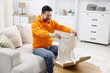 © New Africa - Happy man taking sweater vest from open parcel at table on sofa at home