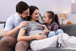 © New Africa - Pregnant woman, her husband and daughter on sofa at home